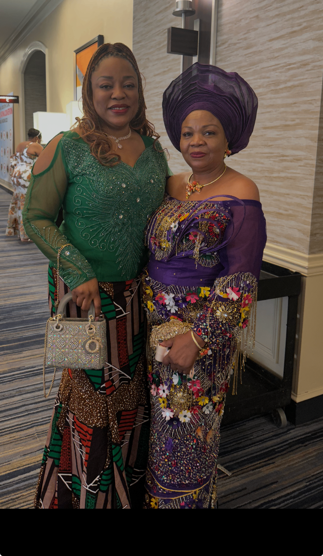 Two Ngwa women in emerald green and purple traditional attire with matching gele at a Dallas–Fort Worth event.